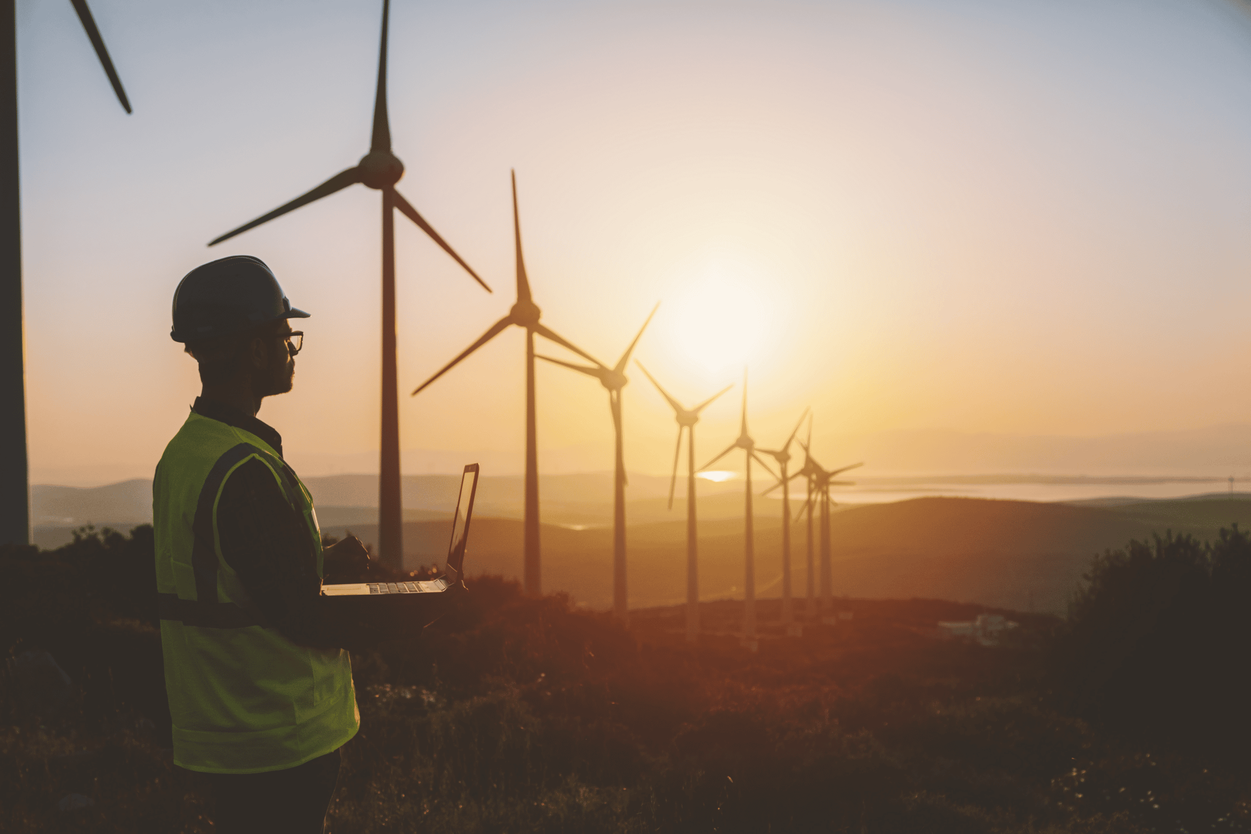 Techniker überwacht Windkraftanlagen bei Sonnenuntergang.